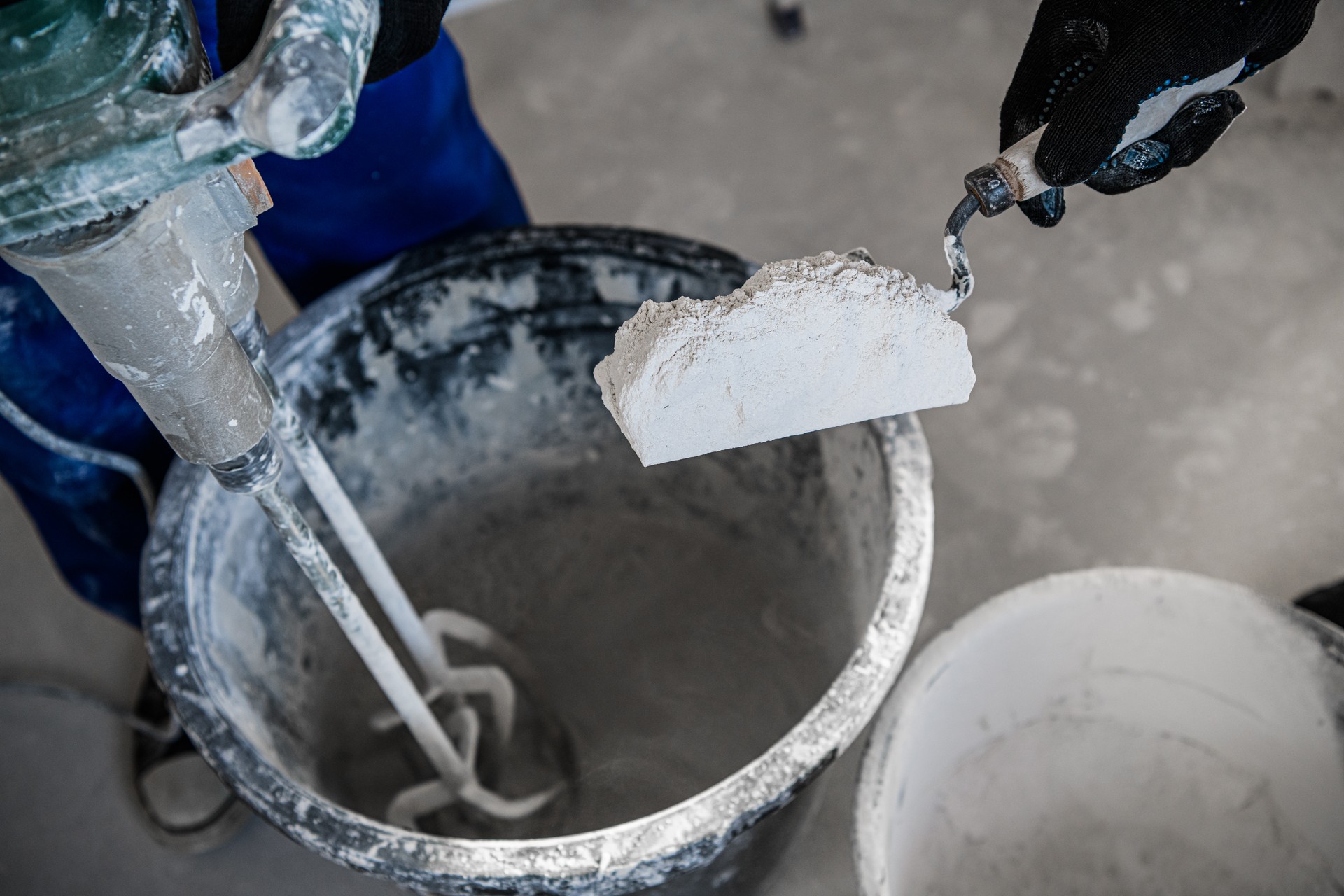 Craftsman put dry cement into a bucket with a spatula